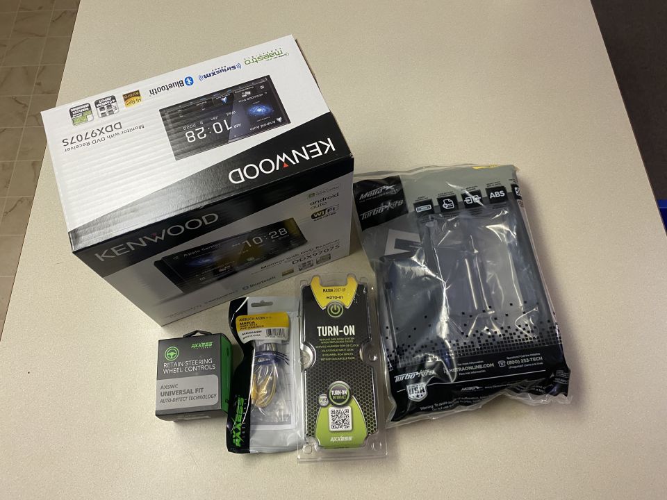 Kenwood DDX9707S car stereo receiver box and accessories on a table.