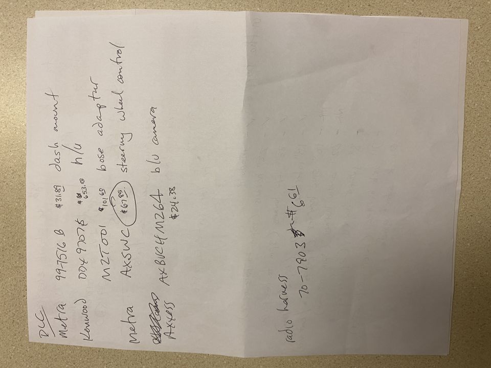 Handwritten list of car parts and prices on a piece of paper.