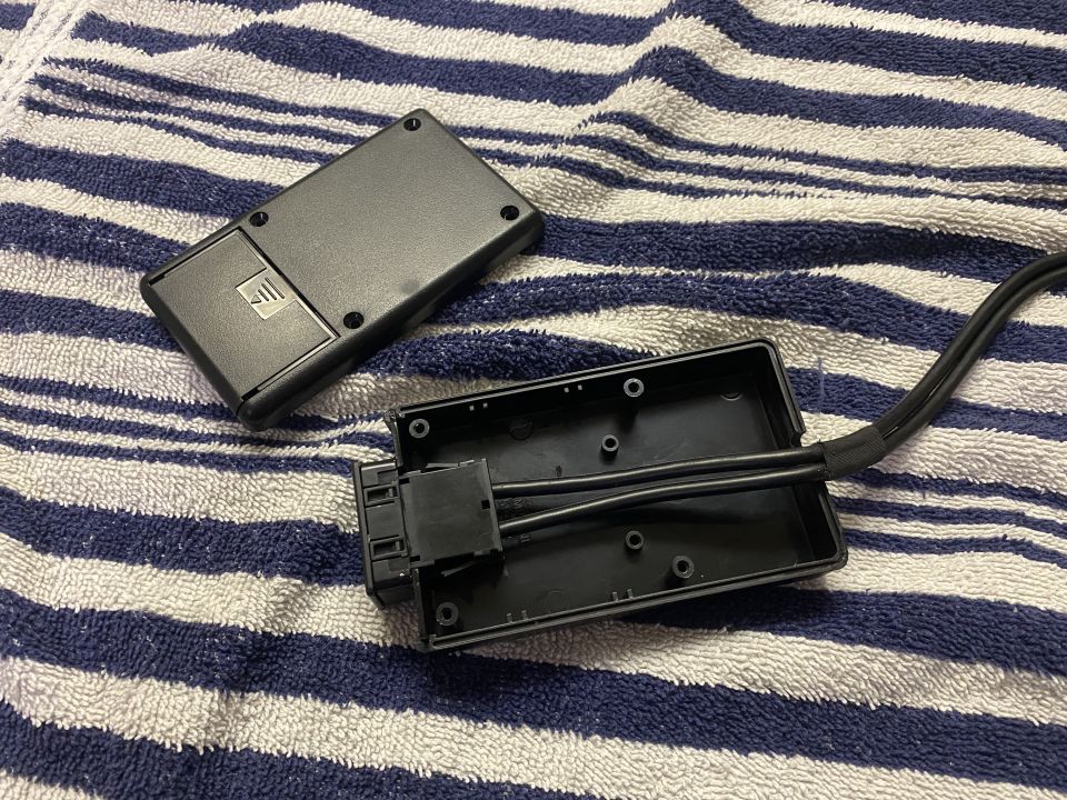 Black electronic device with internal components and wiring, resting on a striped towel.