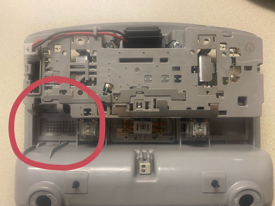 Underside of a gray interior light assembly with wiring and a small grille.