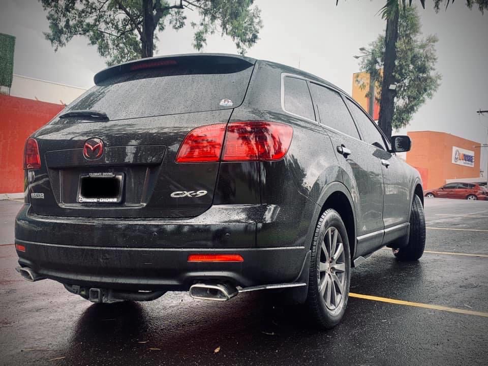 Black 2009 Mazda CX-9 rear passenger side view, parked on a wet street.