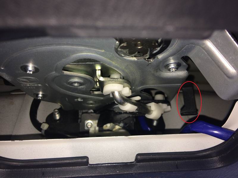 Close-up of a car door latch mechanism with a black lever highlighted.