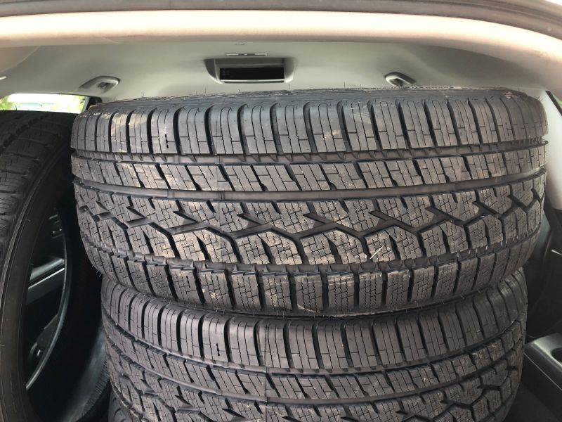 Stack of four tires inside a vehicle cargo area.