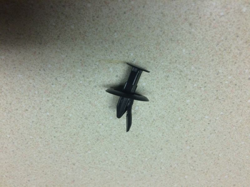 Black plastic automotive clip on a speckled countertop