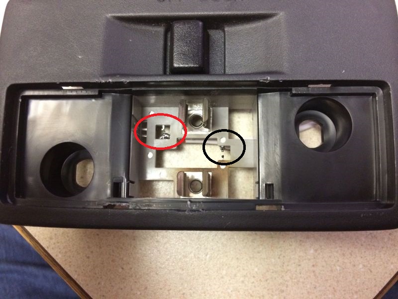 Close-up of a vehicle's interior light fixture housing with metal contacts.