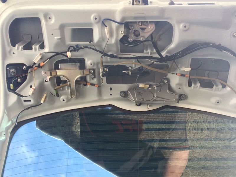 Interior of a car's trunk lid showing wiring, latch, and wiper motor.