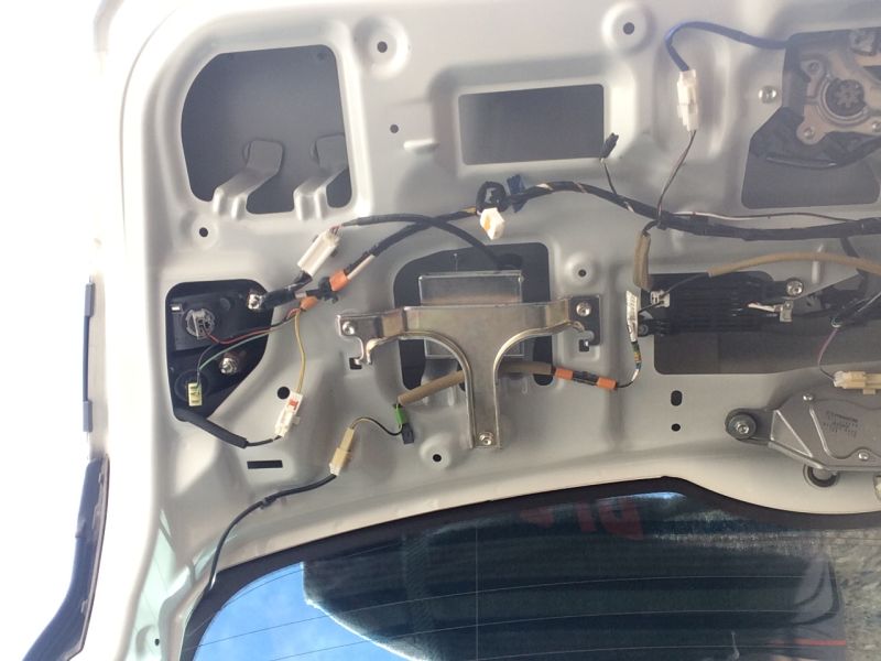 Interior of a white vehicle tailgate with exposed wiring, taillight, and wiper motor.