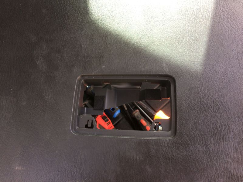 Close-up of black textured surface with cutout showing electrical connectors.