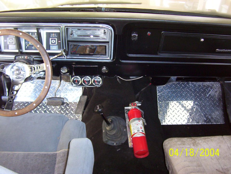 Interior shot of a truck cab, showing dashboard, steering wheel, gauges, gear shifter, and a fire extinguisher