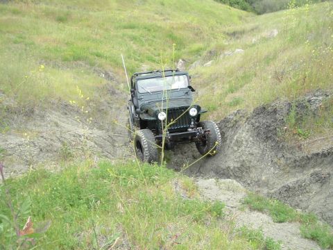 1989 Ford Bronco - Off-road vehicle descends a challenging dirt path surrounded by vegetation.