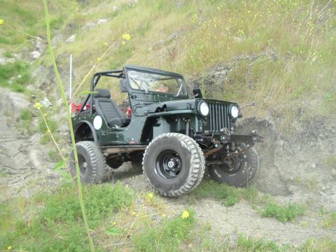 1989 Ford Bronco - This vintage Jeep CJ is navigating a steep, dry, and grassy incline.