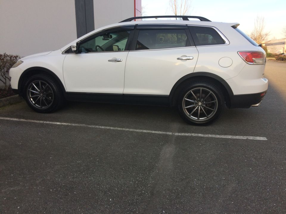Side view of a white 2009 Mazda CX-9 with aftermarket wheels.