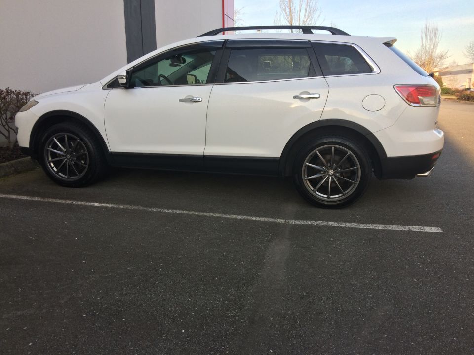 White 2009 Mazda CX-9 SUV parked, side view, with aftermarket wheels and roof rack.