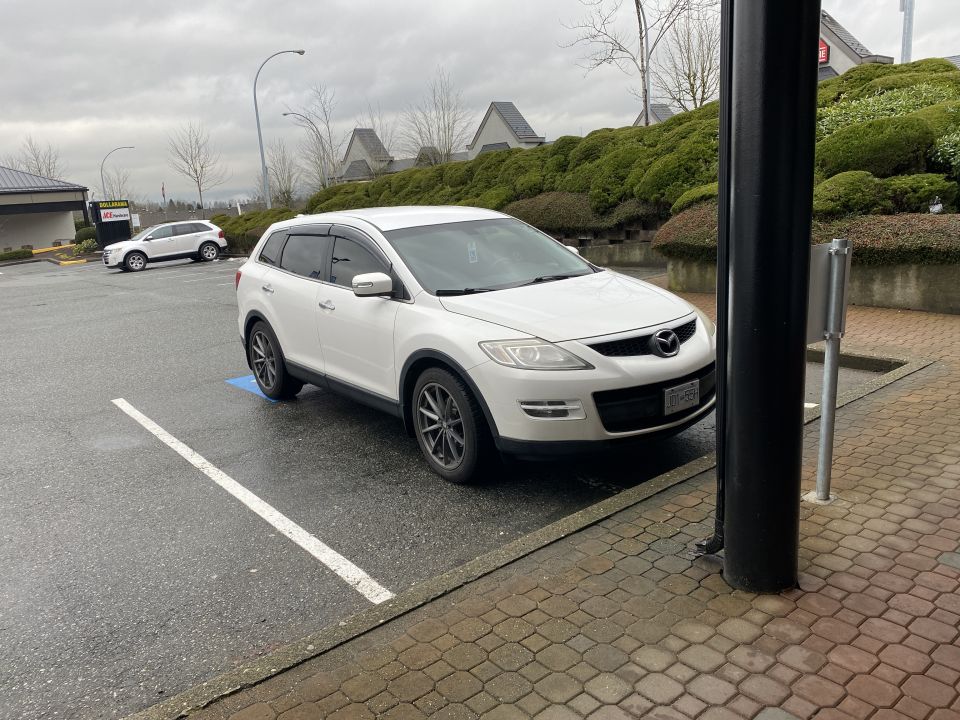 White 2009 Mazda CX-9 SUV parked in a wet parking lot.