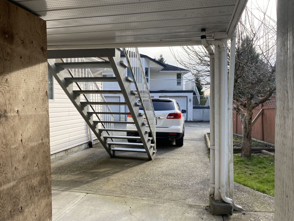White SUV parked in a driveway, seen from the rear.