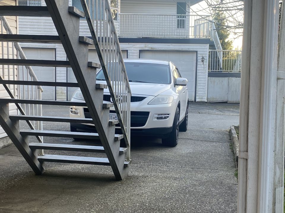 White 2009 Mazda CX-9 parked in driveway with metal stairs in foreground.