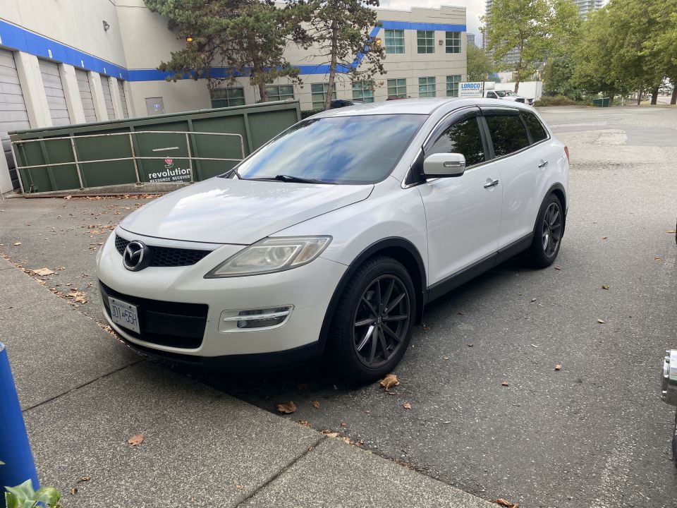 White 2009 Mazda CX-9 SUV parked next to a dumpster