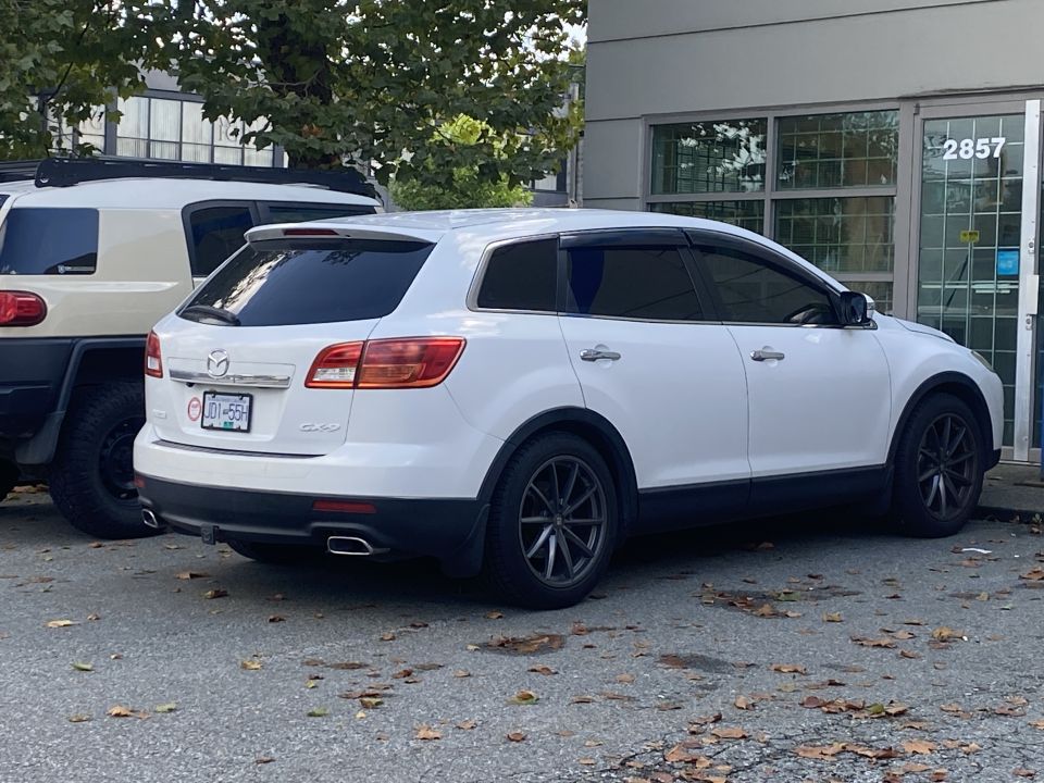 White Mazda CX-9 parked outdoors, rear passenger side view.