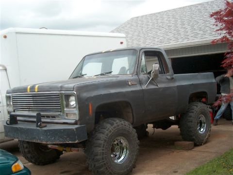 1979 Ford Bronco - This lifted pickup truck features a prominent aftermarket bumper and dual yellow racing stripes on the hood.