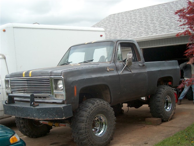 Dark gray lifted pickup truck with yellow racing stripes and aftermarket bumper