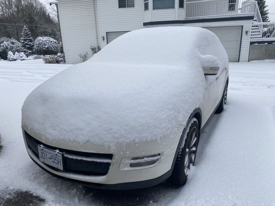 White SUV covered in snow with license plate JDI 55H.
