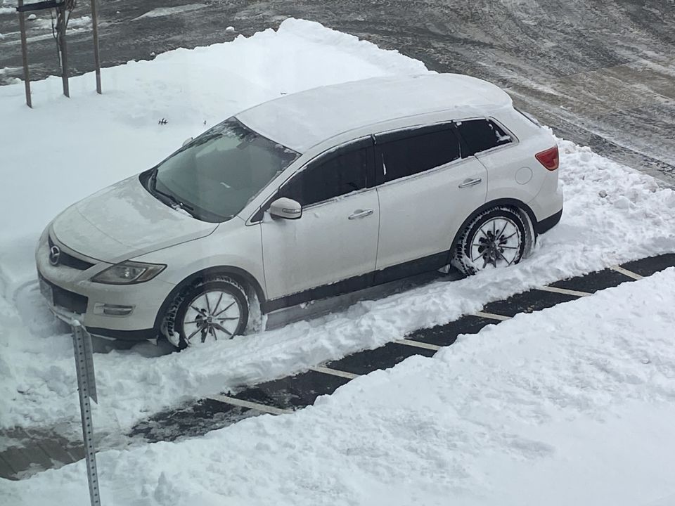 White Mazda CX-9 stuck in deep snow.
