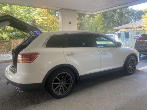 White 2009 Mazda CX-9 with trunk open, parked under a cover.