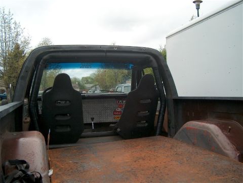 1979 Ford Bronco - The interior of a vehicle shows racing seats, a roll cage, and diamond plate accents.