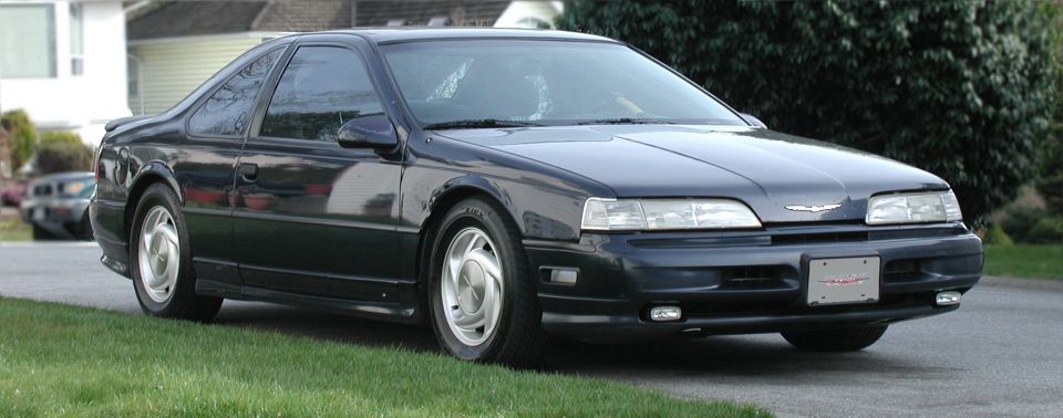 Dark blue 1990 Ford Thunderbird coupe parked on a residential street.