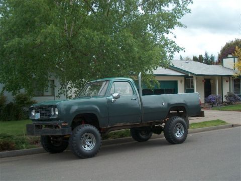 1979 Ford Bronco - This lifted pickup truck is parked on the side of a street in front of a house.