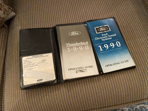 1990 Ford Thunderbird - An open black vinyl booklet displays a 1990 Ford Thunderbird owner's manual and a Ford Electronic Sound Systems operating guide. A warranty…
