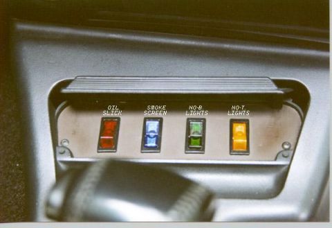 1990 Ford Thunderbird - A close-up view of a dashboard panel with four toggle switches labeled "OIL SLICK", "SMOKE SCREEN", "NO-B. LIGHTS", and "NO-T. LIGHTS". Eac…