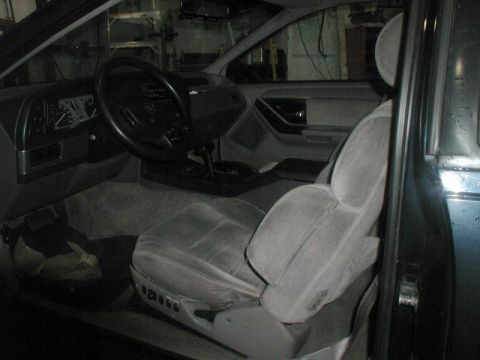 1990 Ford Thunderbird - The interior of a 1990 Ford Thunderbird is shown from the driver's side, featuring a gray cloth seat, dashboard, and steering wheel. The ve…