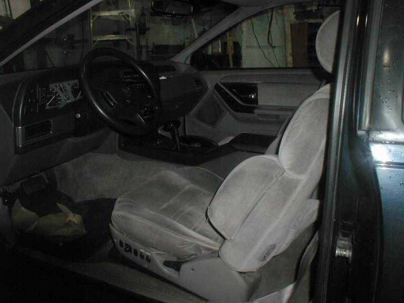 Interior of a 1990 Ford Thunderbird showing driver's seat, dashboard, and steering wheel.