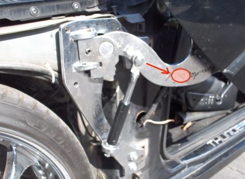 1990 Ford Thunderbird - A close-up view of a custom door hinge mechanism on a vehicle, featuring a gas strut and polished metal components. Text is visible on the…