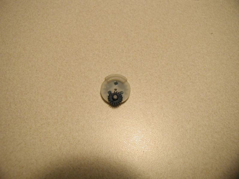 Small dark gray gear on a clear plastic component.