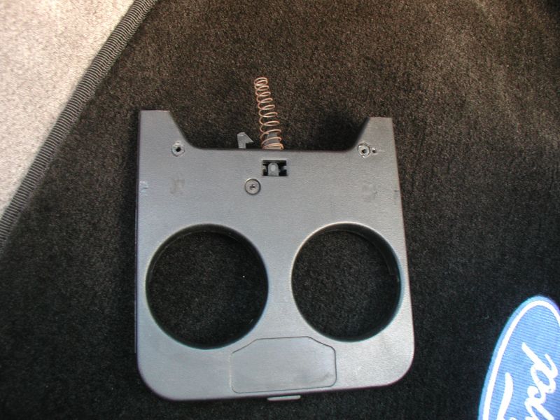 Before you put the cupholder tray in, there is a little trick to get some extra outward movement. Grind down the little tab that would normally act as a stop on the coin tray. Put in a decent size screw, but not to long as to hit the coin tray. Put the screw in the cupholder, about 1/2 to 1 inch from the back edge. Don't set it flush; you want the screw head sticking up a bit so that when you pull the cupholder out it will hit the crossbar and act as the stop. * In the above picture, I have the