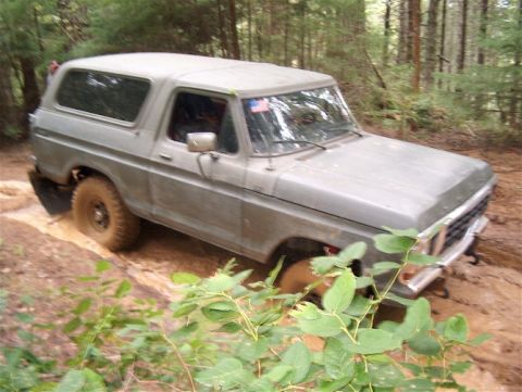 1979 Ford Bronco - This classic Ford Bronco is navigating a muddy path in a forest setting.