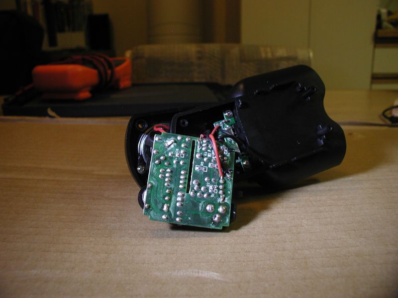 Disassembled electronic device with circuit board and wires on a wooden table.