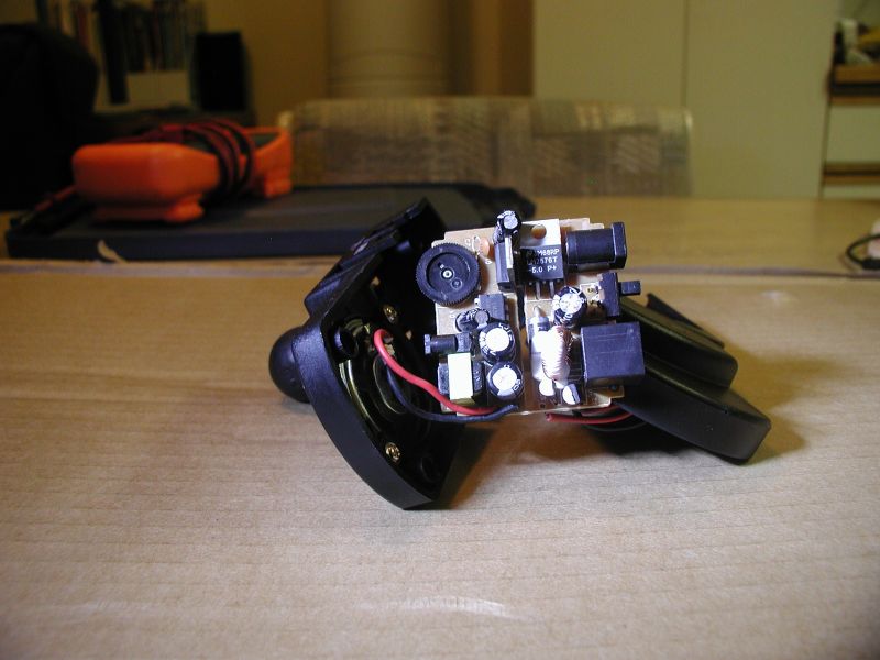 Internal electronics of a black device with wires and circuit board, on a wooden table.