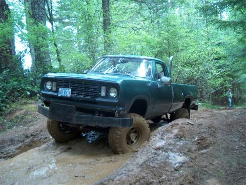 1979 Ford Bronco - This pickup truck is navigating a muddy trail in a wooded area, with a person visible in the background.