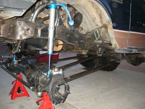1994 Ford Bronco - Custom suspension components are visible on a vehicle undergoing modification, supported by jack stands.