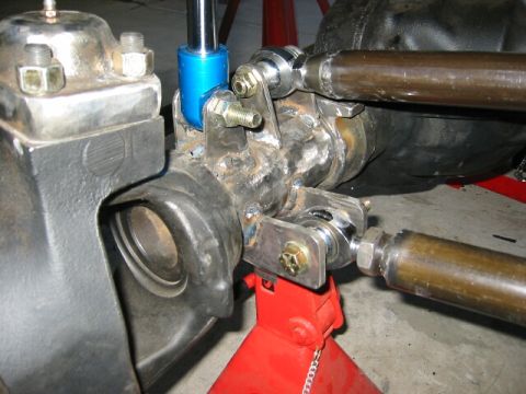 1994 Ford Bronco - Custom suspension components are shown attached to a vehicle's axle, supported by a red jack stand.