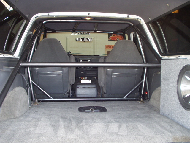 Interior rear view of a truck cab with bolted-in tubular roll cage behind the seats