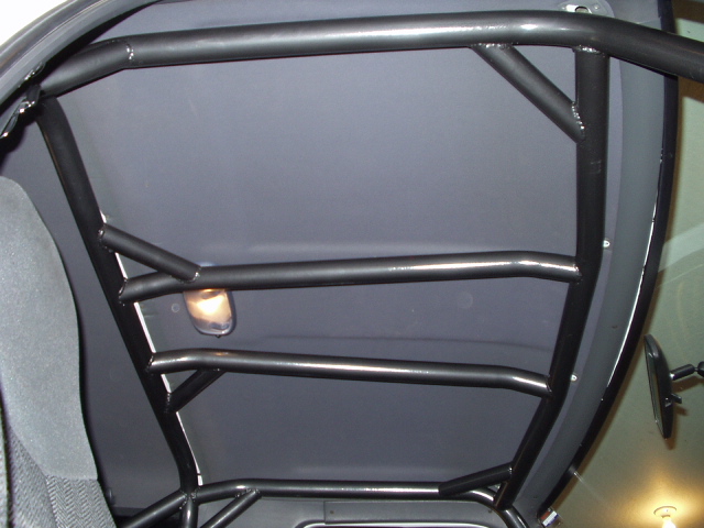 Close-up of black tubular roll cage bars against a vehicle's rear quarter window