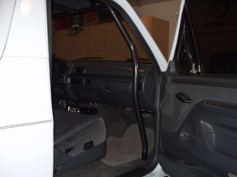 1993 Ford Bronco - Interior of a 1993 Ford Bronco with a roll cage installed. The dashboard and driver's seat are visible.