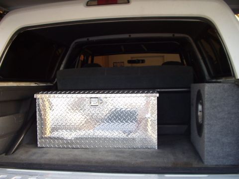 1993 Ford Bronco - The cargo area of a vehicle contains a toolbox and a speaker enclosure.