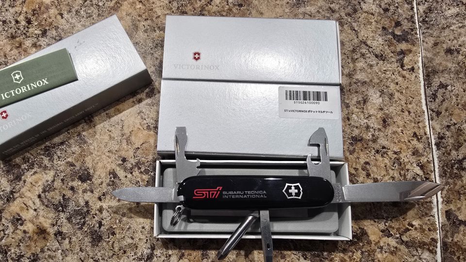 STI-branded Victorinox multi-tool with blades open in its packaging on granite