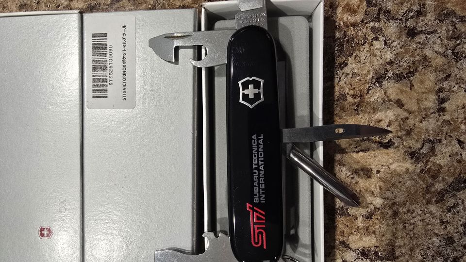 Black STI Victorinox pocket knife with tools open, lying in its gray box