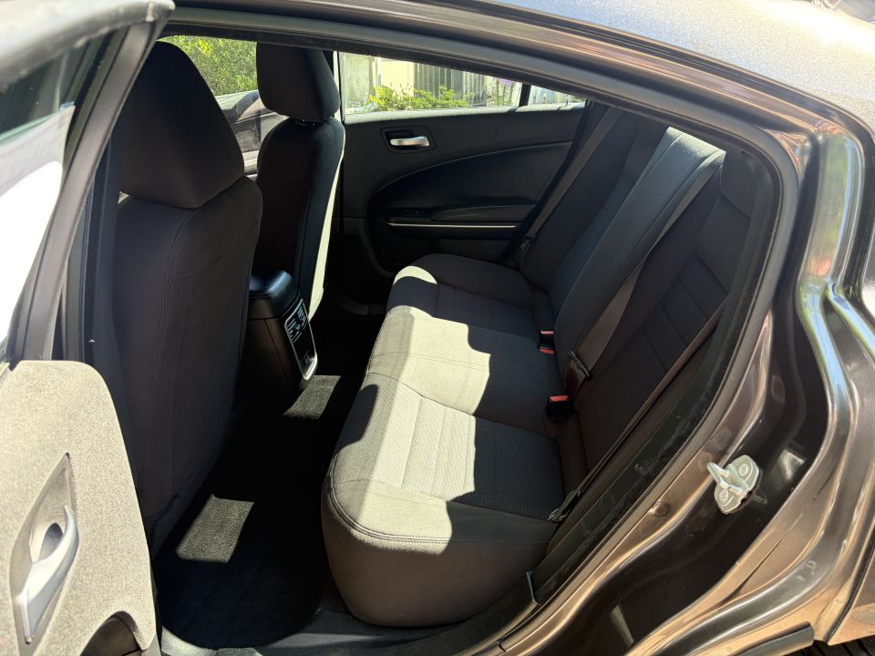 Open rear door view of a sedan's black cloth back seat and gray carpeted floor